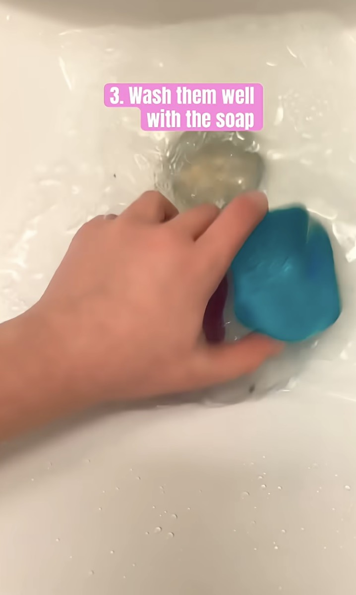 A hand rubbing two NeeDoh cubes together in soapy water