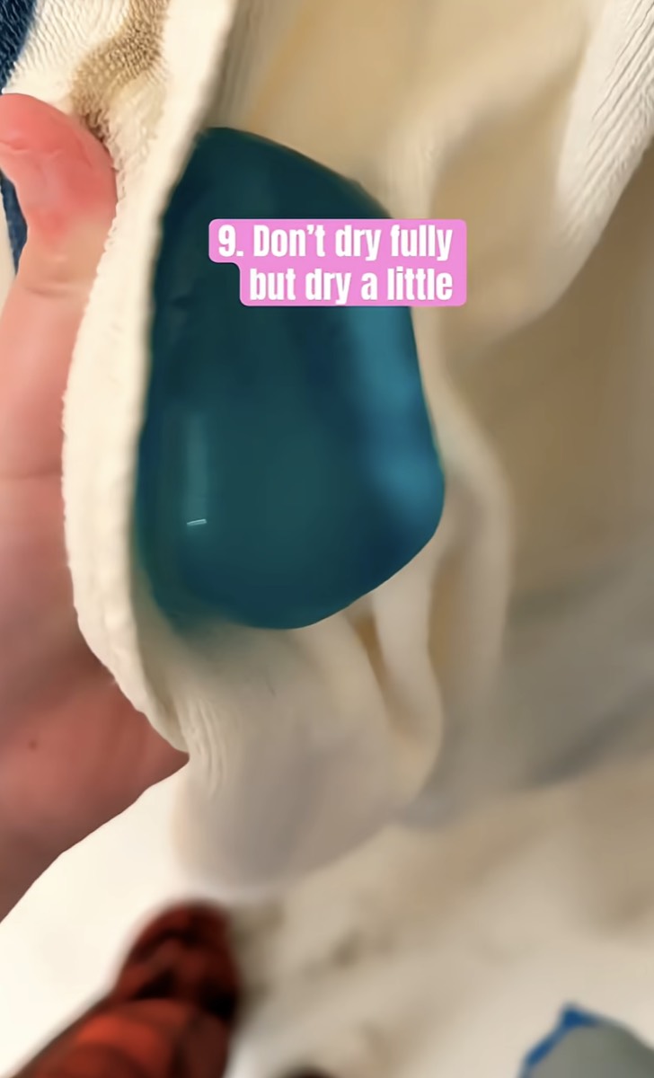 A teal NeeDoh cube blotted lightly in a towel, left slightly damp