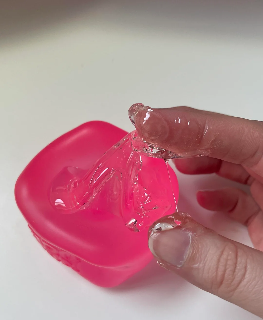Clear maltose filling being pulled out of a pink NeeDoh Nice Cube