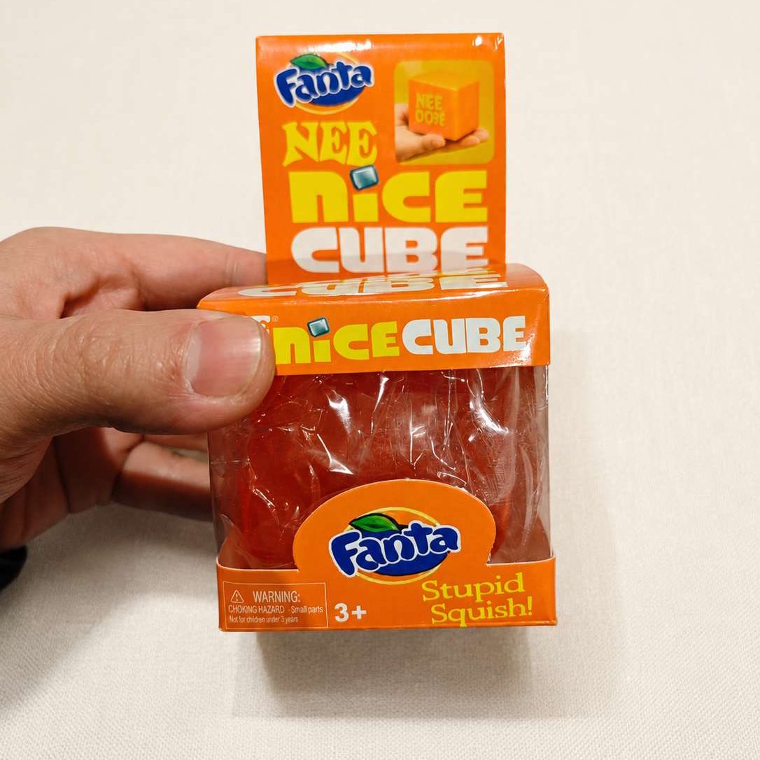 Hand holding the orange Fanta squishy cube inside its Nice Cube carton