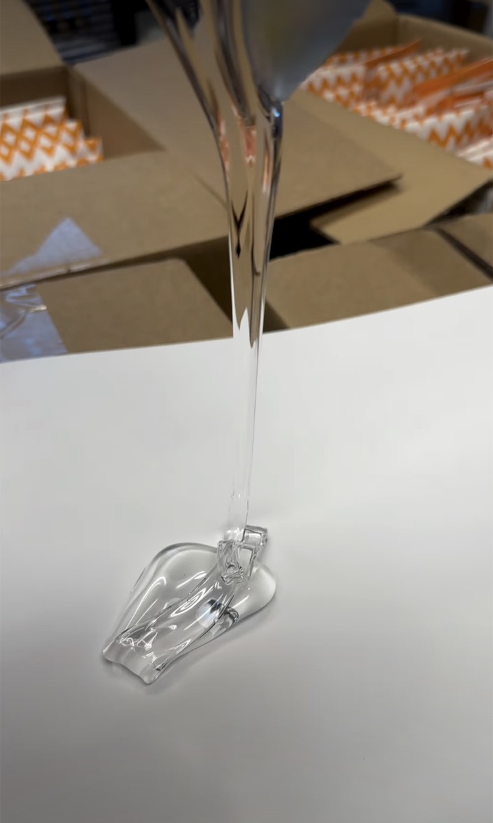 Long clear strand of NeeDoh filling stretching down onto a white table