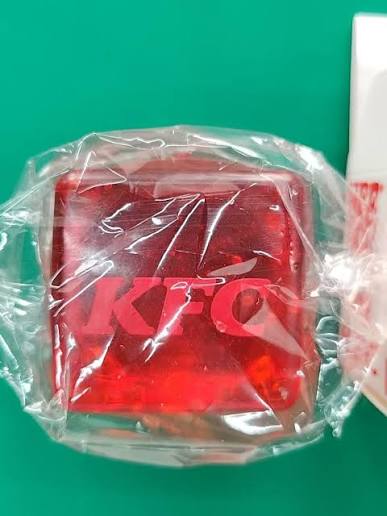 Bare translucent red KFC squishy cube in its plastic wrapper